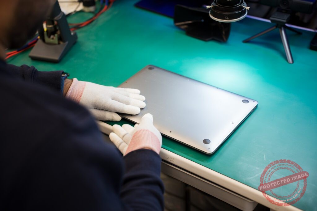 Technician securing MacBook base cover on repair bench
