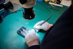 Technician soldering circuit board under microscope at Tech Lab Worthing